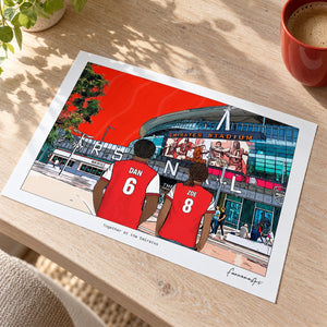Personalised Arsenal couple print on an oak desk, shown unframed in an AI-assisted lifestyle mockup.